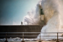 A man escapes a huge wave at Aberystwyth Lighthouse in Wales, by Craig Kirkwood